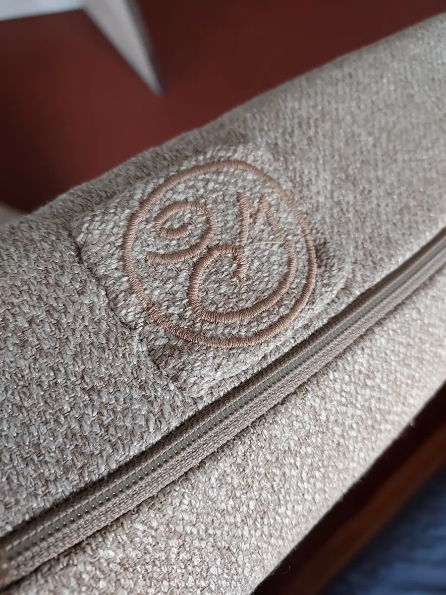 Logo du Coin Coin Couture brodé sur un tissu bouclé beige, à côté d'une fermeture éclair