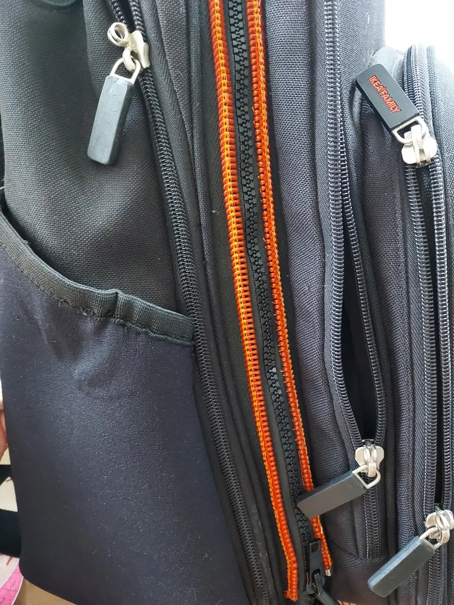 Fermetures éclair d'un sac à dos noir, dont une fermeture neuve à grosses dents noires sur ruban orange
